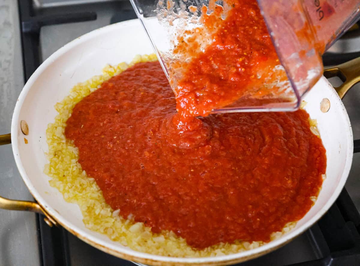 After re-testing this Homemade Marinara Sauce, I can confidently say itโs the BEST! You can make it in 15 minutes, but letting it simmer makes the flavors even better! Blended up ingredients being added to the onions in the saucepan.